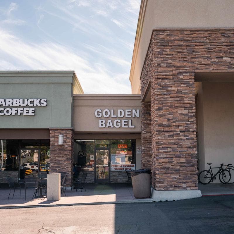 Golden Bagel storefront next to Starbucks in a shopping plaza.