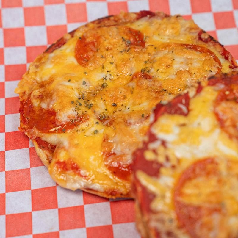 Pepperoni pizza bagel on checkered paper.