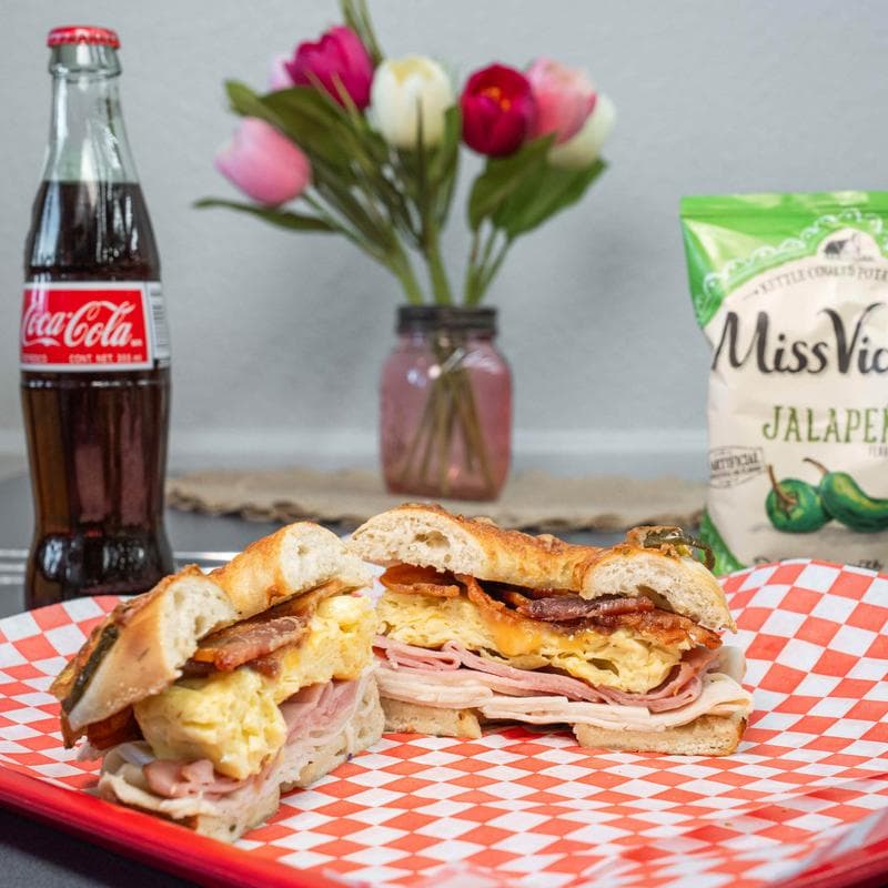 Breakfast bagel served with jalapeno chips and soda.